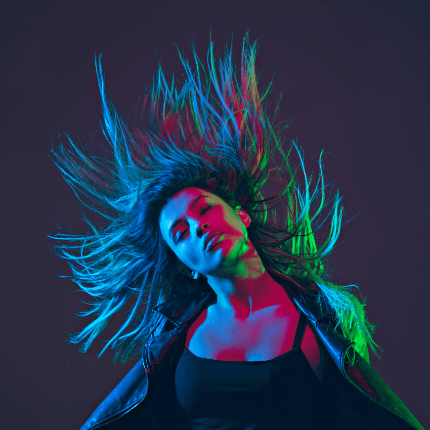 woman with long hair shaking her head in a dim-light setting