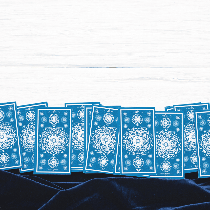 row of blue tarot cards spread out on a white table with a blue velvet tablecloth
