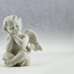 statue of a white porcelain angel sitting peacefully with his hands clasped together