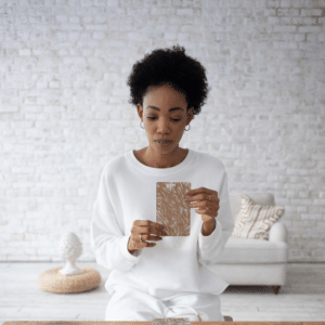 woman wearing all white holding up a large tarot card