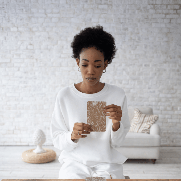 woman wearing all white holding up a large tarot card