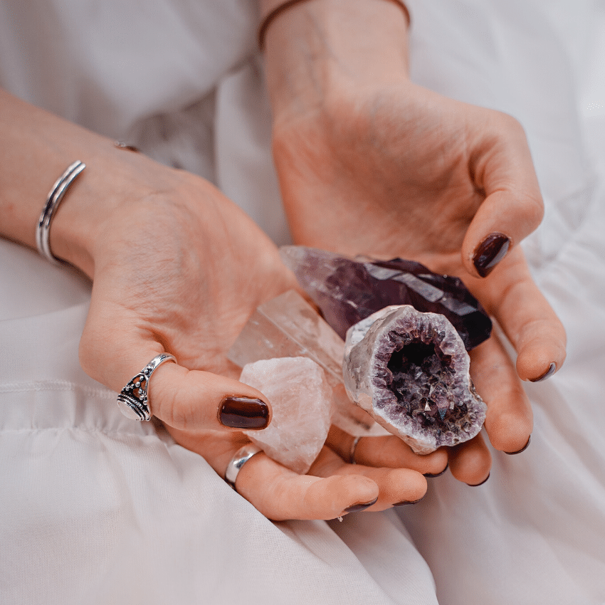 pair of hands holding out a variety of purple crystals