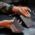 pair of hands shuffling black tarot cards