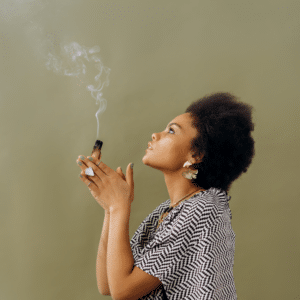 woman in a striped shirt holding burning sage