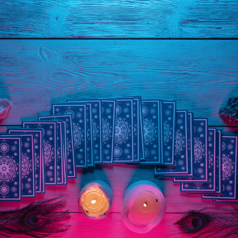 blue tarot cards spread out on a wooden table with candles and feathers