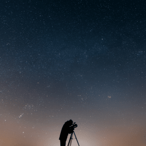 man looking through a telescope at a blue and orange starry night
