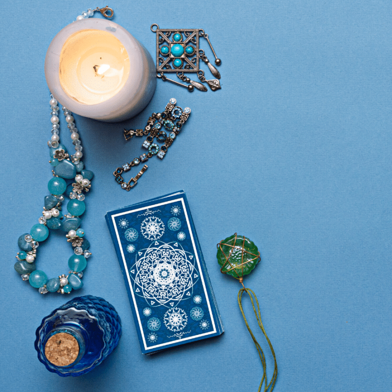 stack of blue tarot cards on a blue table surrounded by candles and blue and green jewelry