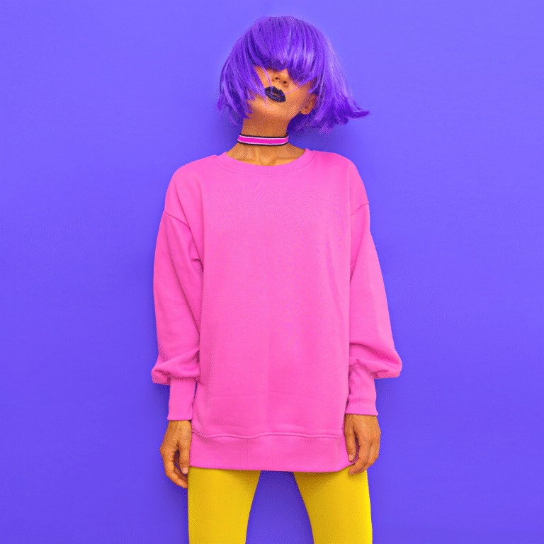 funky woman with short purple hair, pink sweatshirt, and yellow leggings against a purple background