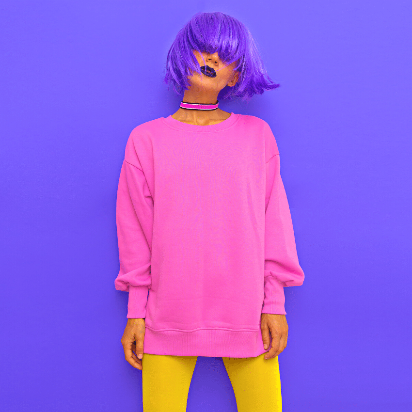 funky woman with short purple hair, pink sweatshirt, and yellow leggings against a purple background