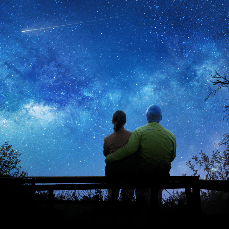 couple sitting and gazing at a blue starry sky