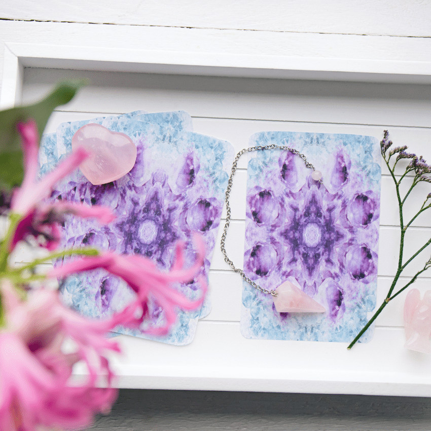 blue and purple angel cards on a white table covered in flowers and crystals