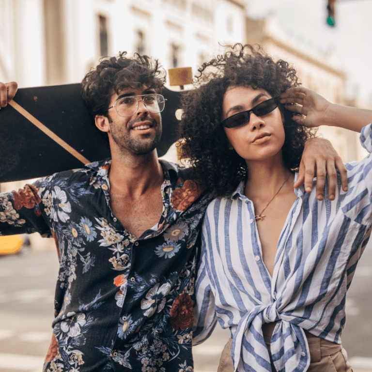 hipster couple walking down a street with sunglasses on holding a skateboard