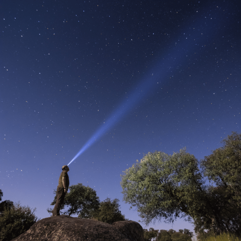 man with a headlamp gazing up at a blue starry sky