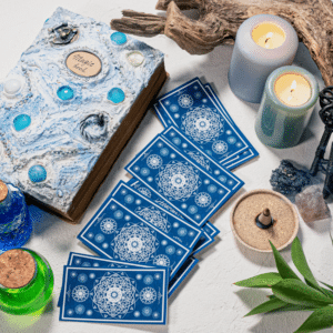 blue tarot cards spread across a white table filled with candles and a magic book