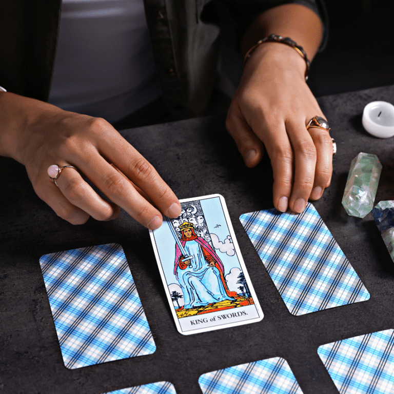 pair of hands holding a king of swords tarot card