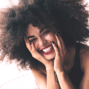 woman with afro and bold red lipstick smiling gleefully