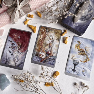 three tarot cards spread across a white table filled with dried flowers