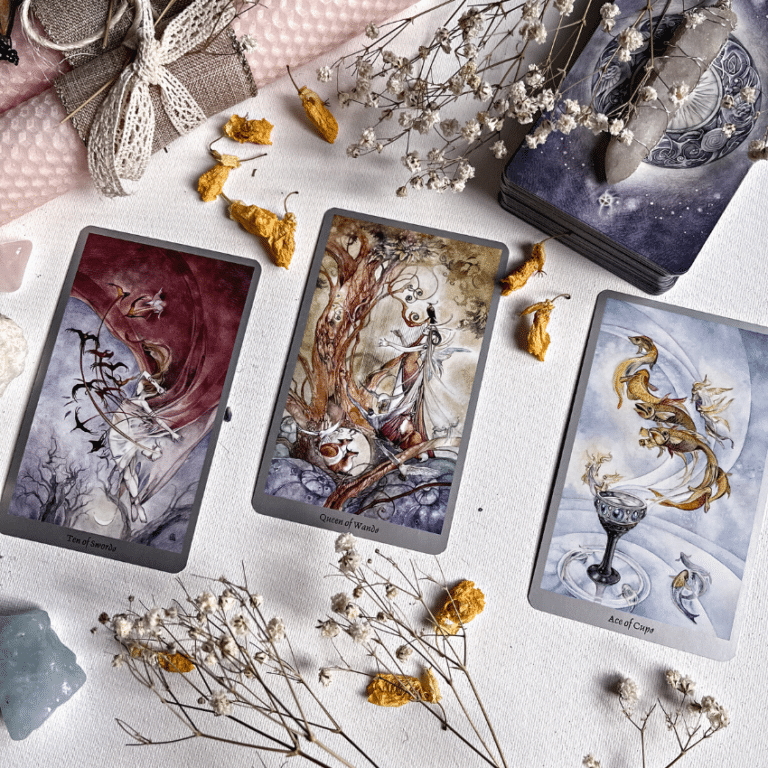 three tarot cards spread across a white table filled with dried flowers