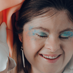 pale, brunette woman smiling with bold blue eyeshadow