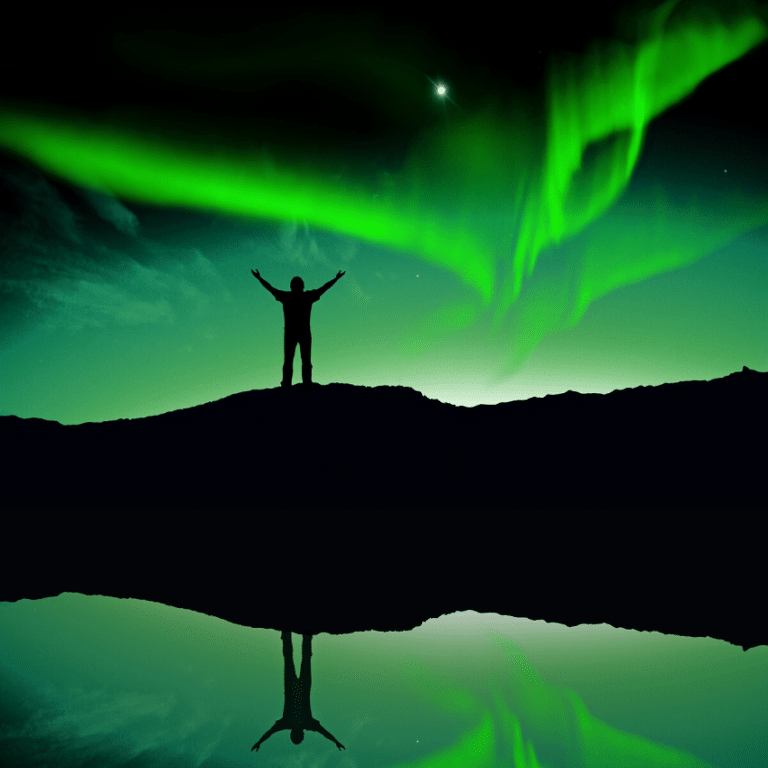 man standing on a hill with his arms outstretched to the green northern lights in the sky