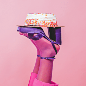 pair of feet in pink stockings and funky purple heels holding up a birthday cake