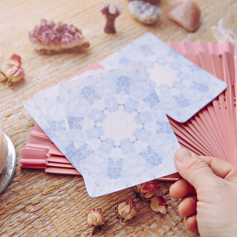 hand holding out a blue angel card above a table covered in candles and crystals