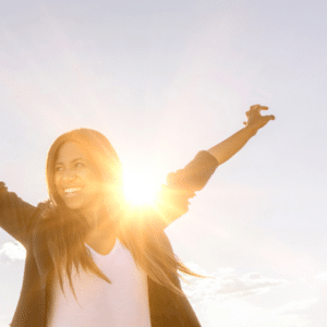 joyous woman with her arms outstretched with the sun beaming on her