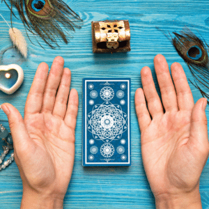 pair of hands outstretched beside a stack of blue tarot cards on a blue table