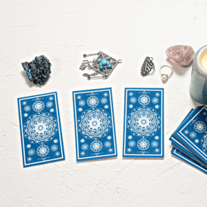 three blue tarot cards spread out on a white table covered in crystals