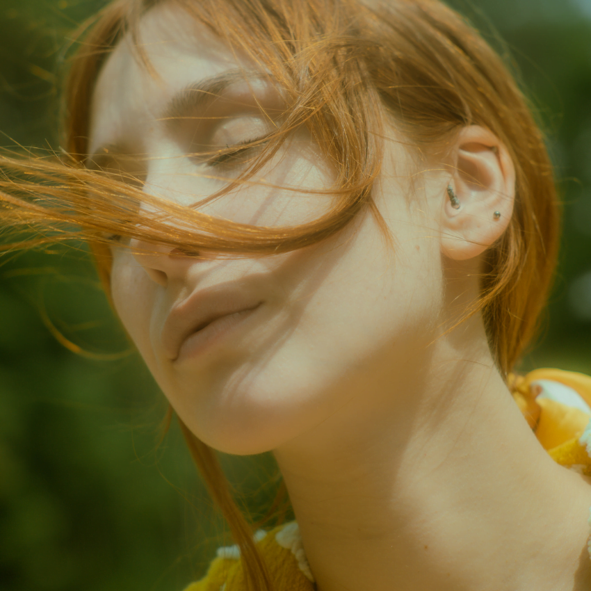 woman with red hair and pale skin with her eyes closed