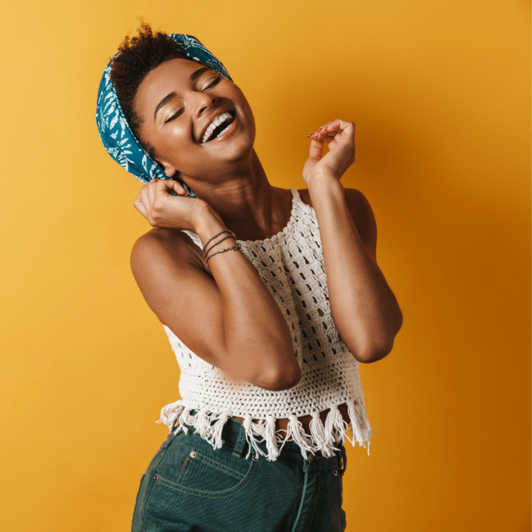 woman smiling gleefully with her head thrown back against an orange backdrop