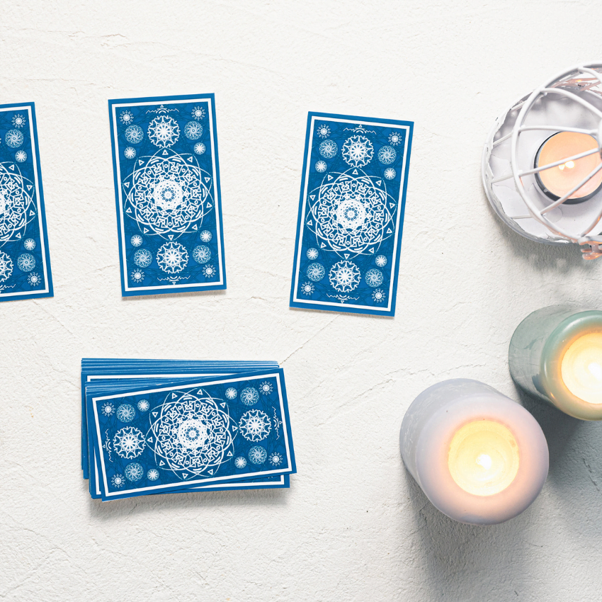 blue tarot cards spread on a white table covered in candles