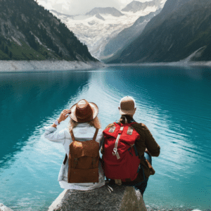 two people sitting on a rock staring ahead over a lake towards mountains