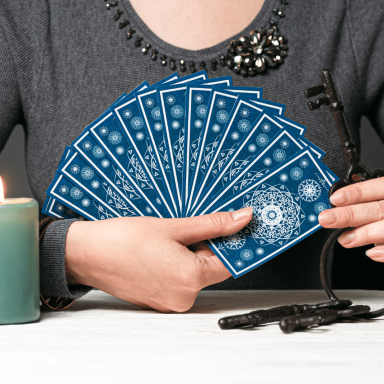hand holding up a spread of blue tarot cards