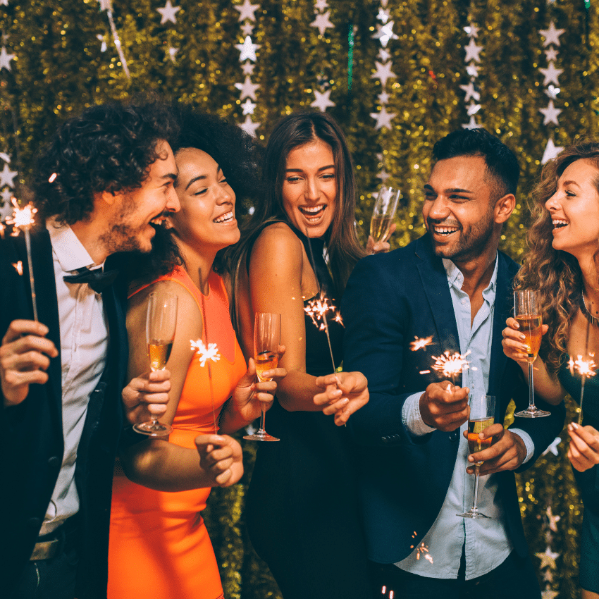 people standing in front of a gold backdrop with sparklers and champagne