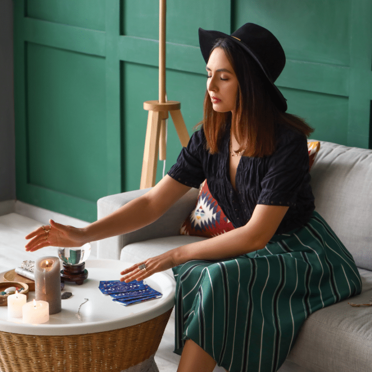woman sitting on a white couch in a green skirt and black shirt reading tarot cards on a table