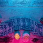 blue tarot cards spread across a wooden table with candles