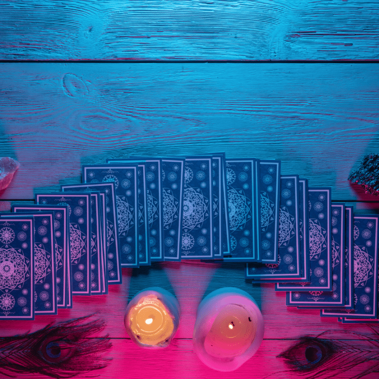 blue tarot cards spread across a wooden table with candles