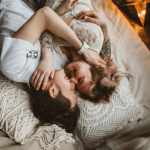 couple laying in bed together laughing and cuddling