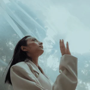 asian woman in a white blazer gazing up at the sky with sheer fabric hanging above