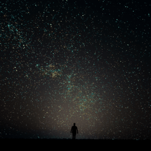 silhouette of a man standing against a dark black starry night