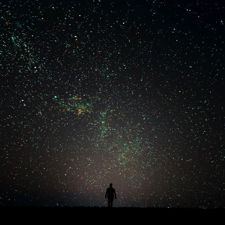 silhouette of a man standing against a dark black starry night