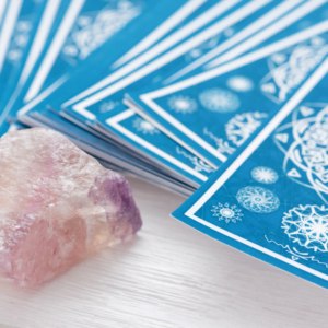 stack of blue tarot cards next to a pink crystal