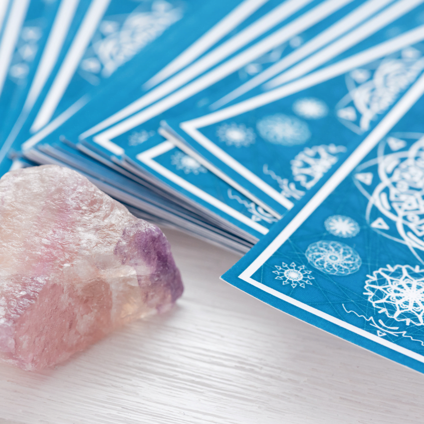 stack of blue tarot cards next to a pink crystal