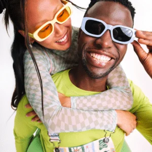 a couple wearing bright sunglasses smiling to represent a synastry reading