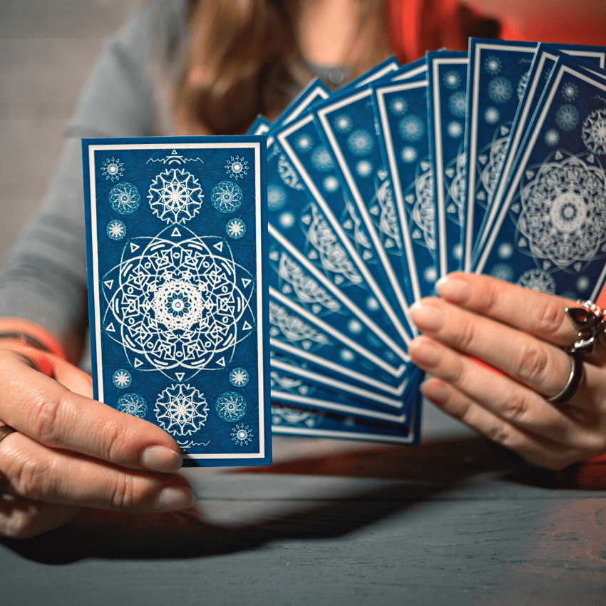 pair of hands holding up blue tarot cards