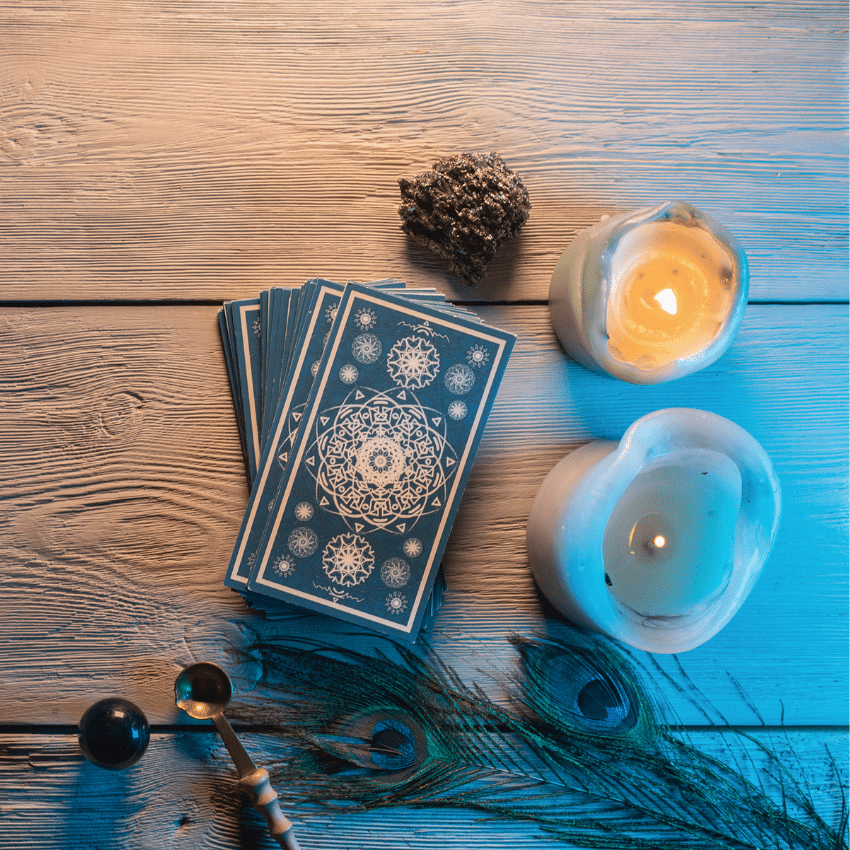 blue tarot cards on a wooden table surrounded by candles and crystals