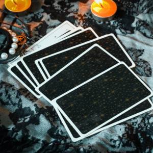 pile of black tart cards on a table with candles