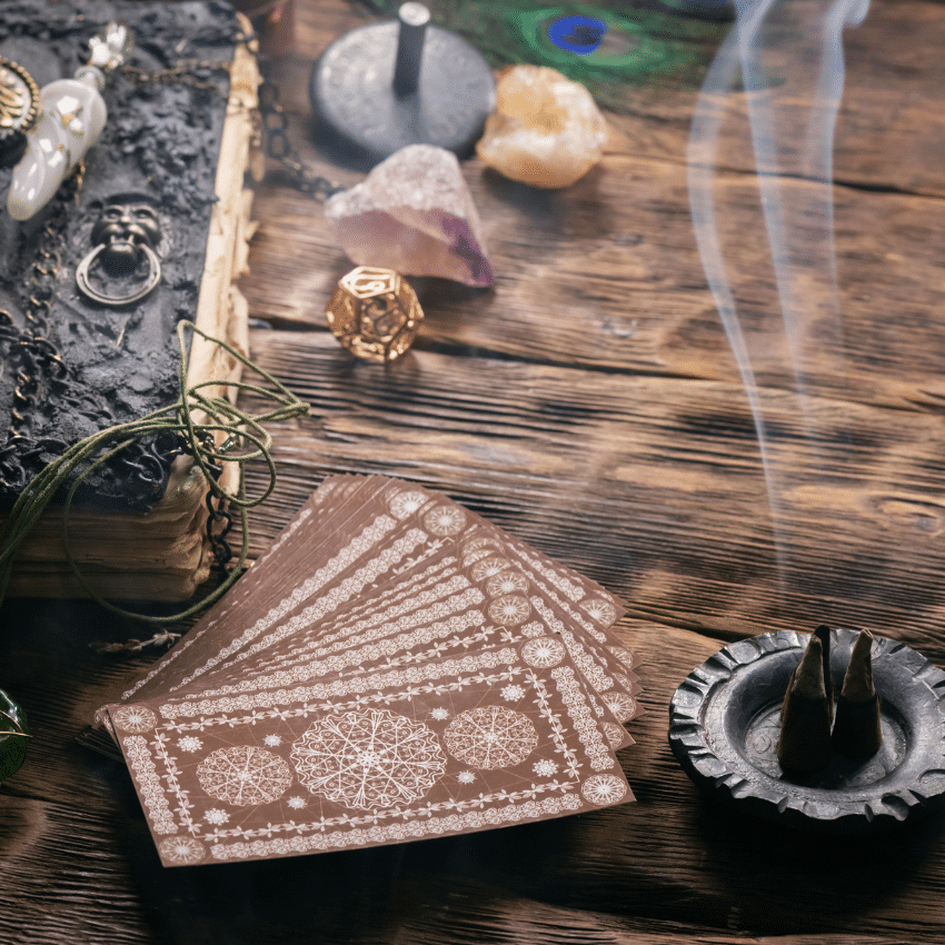stack of brown tarot cards on a wooden table covered in crystals and candles