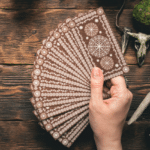 outstretched hand holding a spread of brown tarot cards